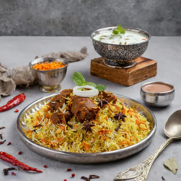  Hint baharatlı koyun eti biryani ve raita gri arka planda servis edilir.