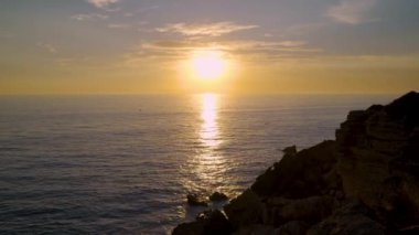 Güneşin yansımasıyla denizin üzerinde gün batımı altın ve turuncu tonlarda bir iz oluşturuyor. Bulutlarla dolu güzel bir yaz günü..