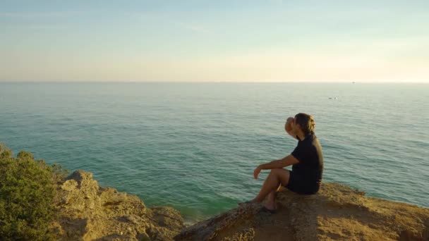 人坐在沙滩的悬崖上 背景是海水 晴天是蓝天 晴天是云彩 形成了概念 来自Calitas Conil Frontera或Calas Roche Cadiz — 图库视频影像