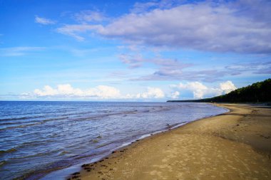 Güneşli bir yaz gününde, baltık sahili. Mavi gökyüzü, beyaz bulutlar ve hiç insan yok.