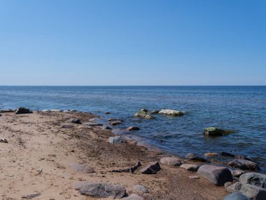 Kum plajı kayalar ve tahta çubuklarla özetlenmiş.