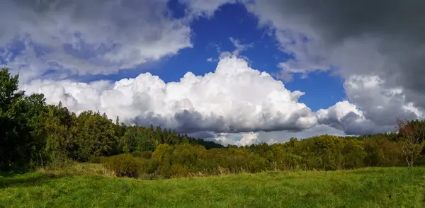 white rain clouds over countryside in summer with blue sky and high contrast