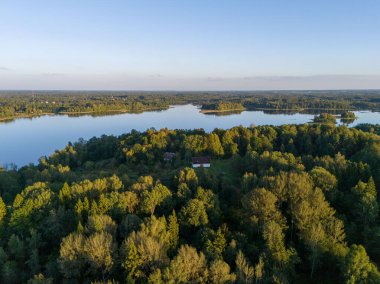 Yoğun yeşil ormanlarla çevrili sakin bir göl manzarası doğanın sakin güzelliğini yansıtıyor..