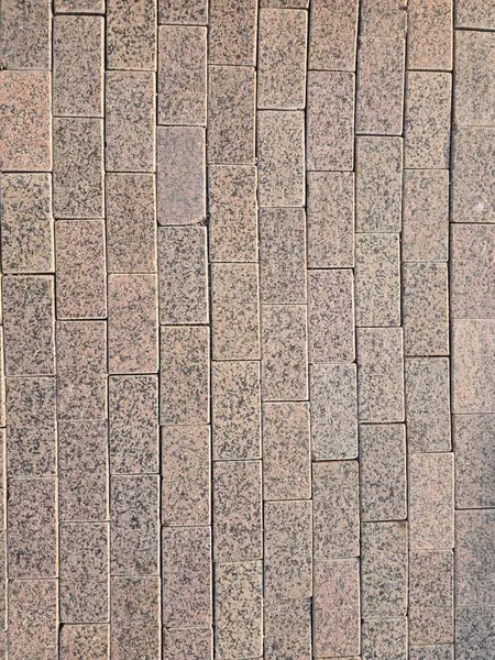 Gri ve pembenin tonlarında dikdörtgen granit kaplamalı, mimari ve tasarım için ideal bir kaldırım manzarası..