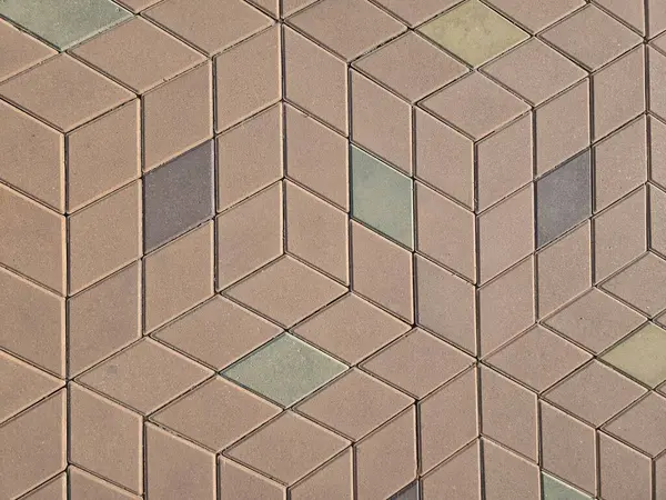 Kahverengi, gri ve yeşil elmas şekilli karolarla desenli bir kaldırımın yakın çekimi mimari ve açık hava projeleri için desenli, modern bir tasarım yaratıyor..