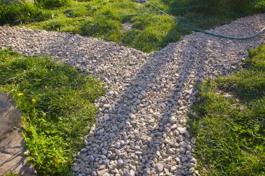 Intersection of decorative gravel paths in a rustic grass yard. Pretty paths in the garden in the rays of the sunset.  clipart