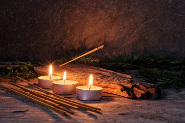 Aromatik tütsü konisi ve dumanı kırsal ahşap masadaki küçük mumlarla çevrili.