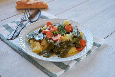 Kırsal ahşap masada patates ve havuçla pişirilmiş yeşil fasulye.