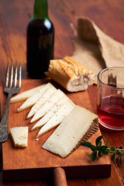 Mutfak tahtasında İspanyol manchego peyniri tapas ve bir bardak şarap.