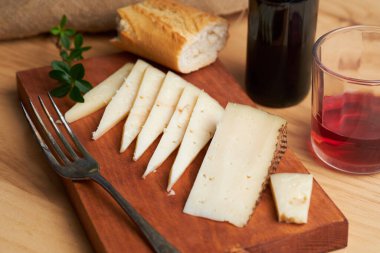 Mutfak tahtasında İspanyol manchego peyniri tapas ve bir bardak şarap.