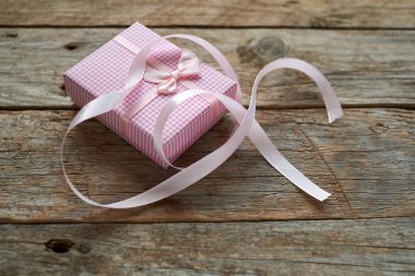 Kırsal ahşap masa üzerinde pembe hediye paketi ve kopyalama alanı