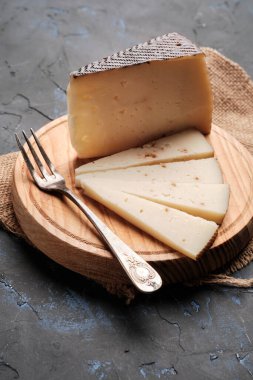 Tahtada, çatallı ve dikey arka planda koyu renk İspanyol peyniri var.