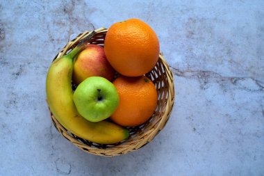 Hasır sepet ve mermer taşın üstünde taze meyveler. Taze, sulu, renkli ve sağlıklı meyveleri sepette karıştır..