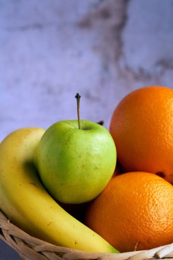 Portakallı yeşil elma ve hasır sepetin içinde muz..