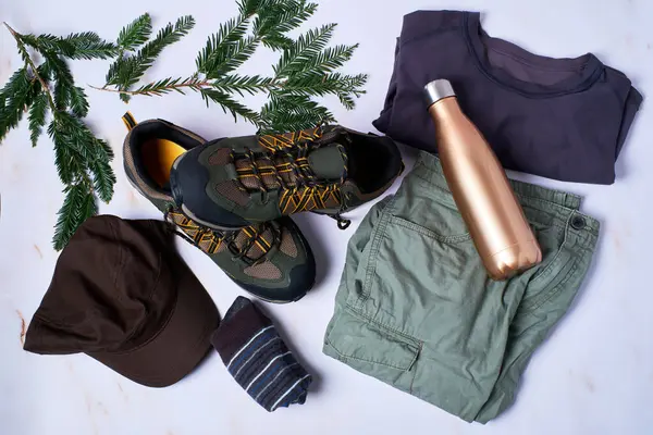 Boots, men's hiking clothing and aluminum thermos. Adventure footwear and summer clothing.