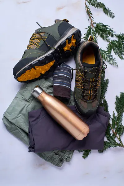Boots, men\'s hiking clothing and aluminum thermos. Adventure footwear and summer clothing.