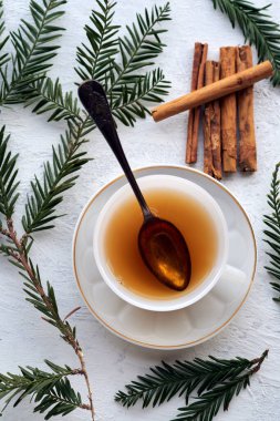 Siyah çay ve tarçın çubuklu beyaz bir seramik bardak.