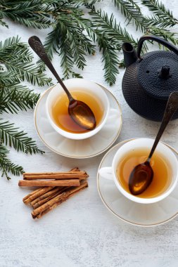 Siyah çay ve tarçın çubuklu iki beyaz seramik bardak.