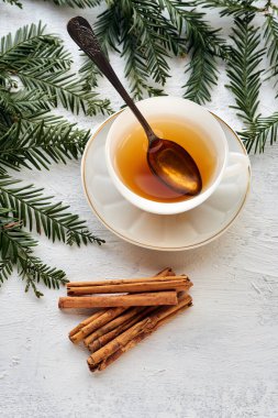 Siyah çay ve tarçın çubuklu beyaz bir seramik bardak.