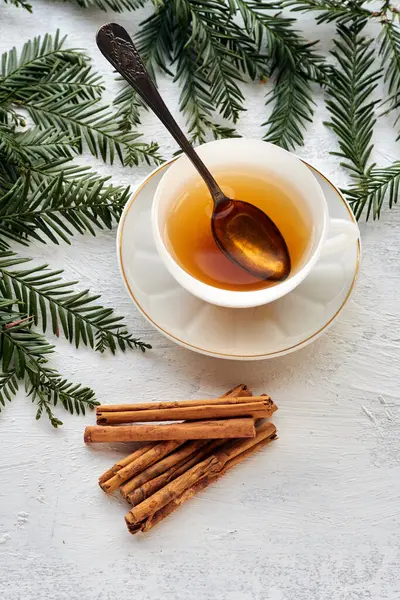 Siyah çay ve tarçın çubuklu beyaz bir seramik bardak.