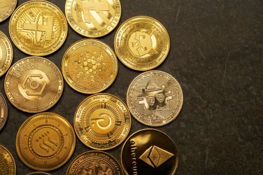 Koyu taşlı arka plan ve yukarıdan görüntülenmiş çeşitli kripto para birimlerinin arkaplanı