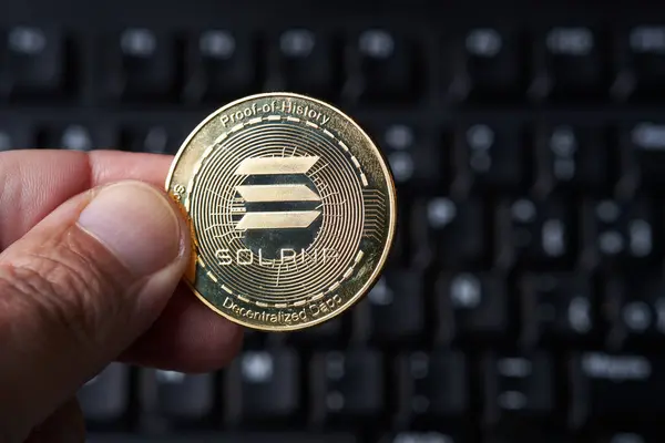 Solana暗号化を保持する手は オンライン取引と仮想通貨投資を象徴するコンピュータキーボードの前に表示されます 背景にはラップトップのキーが含まれており 現代のウールの金融のデジタル性質を強調しています ロイヤリティフリーのストック画像