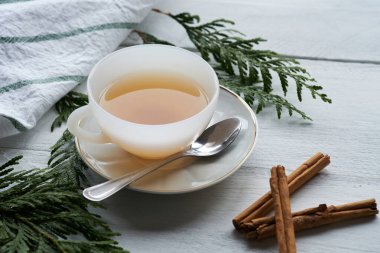 Siyah çay ve tarçın çubuklu beyaz bir seramik bardak.