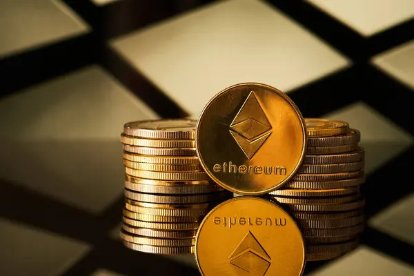Arka planda geometrik deseni olan bir yüzeye yansıyan birçok altın ethereum kripto para birimleri bir yığın içinde düzenlenmiştir..