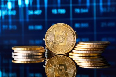 Altın Binance kripto para yığınları pürüzsüz bir yüzeye yansımakta olup, arka planda piyasa eğilimlerini gösteren canlı dijital ticaret grafiği teknolojiden anlayan finansal ortamı vurguluyor..
