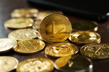 Parlak kripto para koleksiyonu ahşap bir masaya yayılmış, ortada açıkça görülebilen bir Vethor sikkesi, ortam ışığı altında parlıyor.