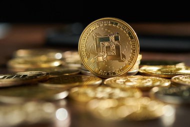 Parlak kripto para koleksiyonu ahşap bir masa üzerine yayılmış, Binance madeni para açıkça ortada görünür, çevre ışığı altında parlayan.