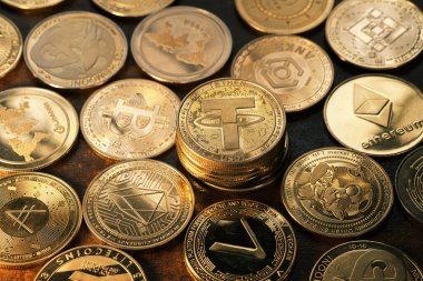 Karanlık bir yüzeyde çeşitli kripto para birimleri sergileniyor. Bağlayıcı, karmaşık tasarımlar ve logolar sergiliyor. Dijital finans piyasasının artan popülaritesini yansıtıyor..