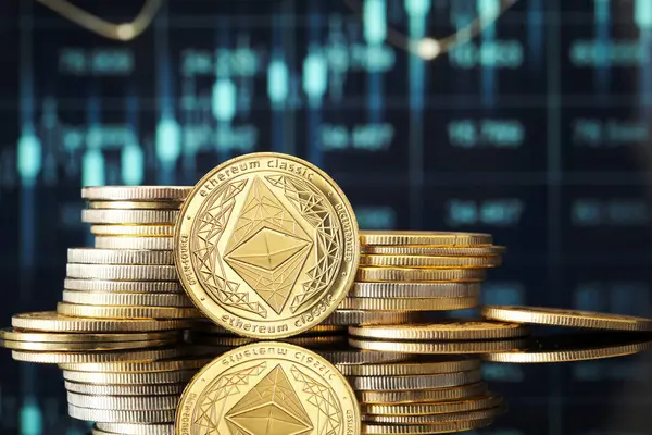 Altın Ethereum Klasik sikkeleri parlak bir yüzeye istiflenmiş, dijital grafikler ticaret eğilimlerini ve pazar verilerini yansıtıyor ve kripto para biriminin büyümesini vurguluyor.