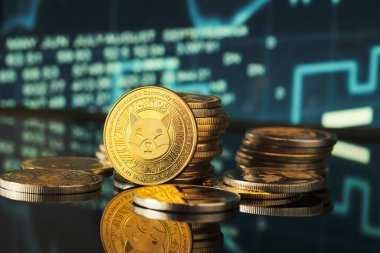 Grafikler arka planda kripto para eğilimleri gösterirken, parlak Shiba jetonlarının yığınları zarif bir şekilde yansıtıcı bir yüzey üzerinde düzenlenmiştir.