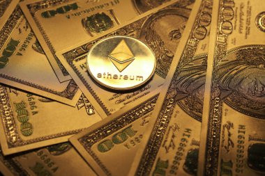 Altın Ethereum madeni parası, modern ekonomide kripto para ve geleneksel finans arasındaki ilişkiyi gösteren bir yığın doların üzerinde duruyor..