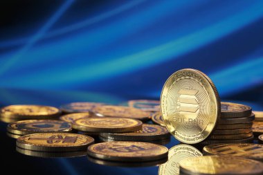 Parlak bir yüzeye yayılmış altın Solana kripto para birimleri. Arkaplanda şifreli para birimi temasını vurgulayan canlı bir mavi dijital kalıp yer alıyor..