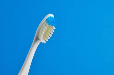 Bu diş fırçası, günlük ağız temizliği rutinleri için ideal, mavi ve beyaz tüyleri olan, parlak mavi bir arka plana yerleştirilmiş parlak bir tasarıma sahip..