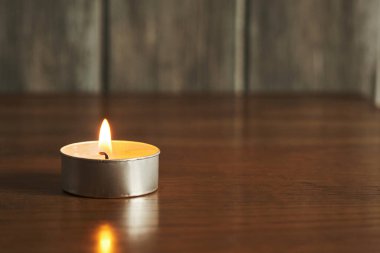 Küçük bir mum ahşap bir masada sürekli yanar. Odanın rahat atmosferini arttıran sıcak bir parıltı yayar. Huzurlu bir ortam yaratır..