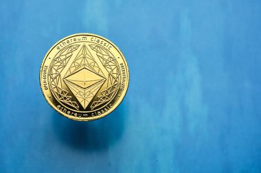 Karmaşık tasarımları olan altın bir Ethereum kripto para birimi, çağdaş finans ve yatırımda dijital para birimlerinin yükselişini sembolize eden mavi bir zemin üzerine kurulmuştur..