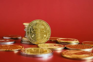 Parlak kırmızı bir zemin üzerinde belirgin bir şekilde bir altın zincir kripto para koleksiyonu sergilenmektedir. Sikkeler dijital para birimi kavramlarını temsil ediyor ve finans ve yatırımı vurguluyor.