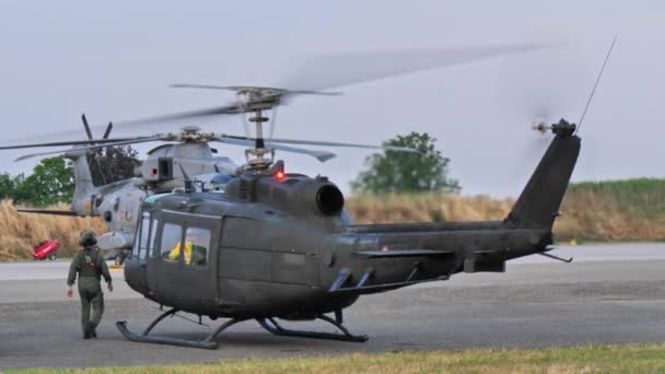 意大利皮亚琴察June 2022年6月15日 身着飞行服和头盔的军事飞行员 坐在一架身着深绿色迷彩服的历史性军用直升机旁边 发动机在起飞前一直在运转 Agusta Bell Ab205 Huey — 图库视频影像