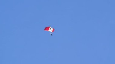 Axalp İsviçre 19 Ekim 2022 Parlak bir ışıkla bulutsuz mavi gökyüzüne düşen tek bir paraşütçü. Beyaz çizgili kırmızı paraşüt.