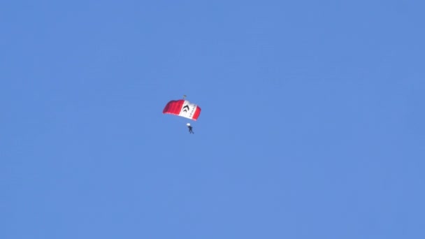 2022年10月19日 瑞士阿克塞尔普号 Axalp Switzerland 的单人跳伞运动员在阳光灿烂的晴天中 在无云的蓝天中坠落 带有白色条纹的红翼降落伞 — 图库视频影像