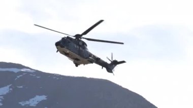 Dar bir dağ vadisinde yüksek hızda uçan askeri helikopter, parlak ve güneşli bir günde yanaşır ve işaret fişeği atar. Ebenfluh atış poligonunda İsviçre Hava Kuvvetleri 'nden Eurocopter AS532 Cougar