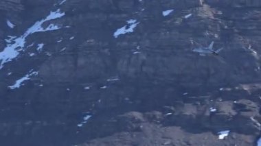 Üstünden uçtuğu dağın kayalık yüzüyle kamufle olmuş askeri bir jet uçağının fantastik videosu. İsviçre Hava Kuvvetleri 'nden McDonnell Douglas F-18 Hornet. Axalp, Bernese Oberland 'da atış poligonu gösterisi yapıyor.
