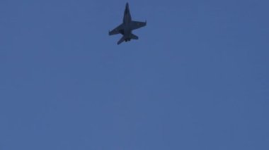 Mavi gökyüzünde kanatlı İsviçre bayrağı taşıyan tek bir savaş uçağı. İsviçre Hava Kuvvetleri 'nden Boeing McDonnell Douglas F-18 Hornet. Axalp, Bernese Oberland İsviçre 'de atış poligonu gösterisi yapıyor.