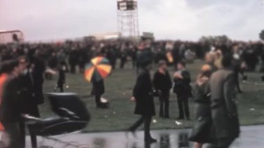 A group of enthusiastic spectators during the rainy weather at the Farnborough Airshow. They are seen walking through the muddy grounds, umbrellas in hand: FARNBOROUGH, UK - Sep 07, 1970. 