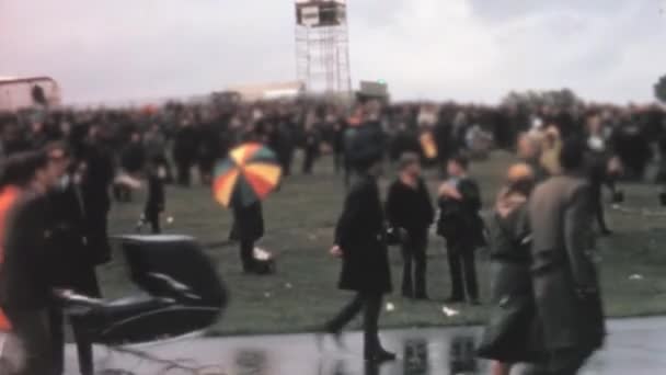 ファーンボロー航空ショーでの雨の天気の間に熱狂的な観客のグループ 彼らは泥だらけの地面 手に傘を歩くのを見られています Farnborogh 1970年9月7日 — ストック動画