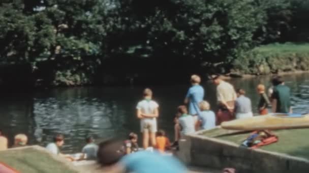 テムズ川の絵のように美しい景色を楽しむ観光客のグループ 川岸に立って 輝く水と周囲の自然景観を見てください イギリスのロングリッジ活動センター — ストック動画