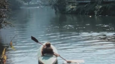 Young man is canoeing on the tranquil waters of the River Thames in the countryside. The serene and peaceful atmosphere of the location with lush greenery in the background. Longridge Activity Centre